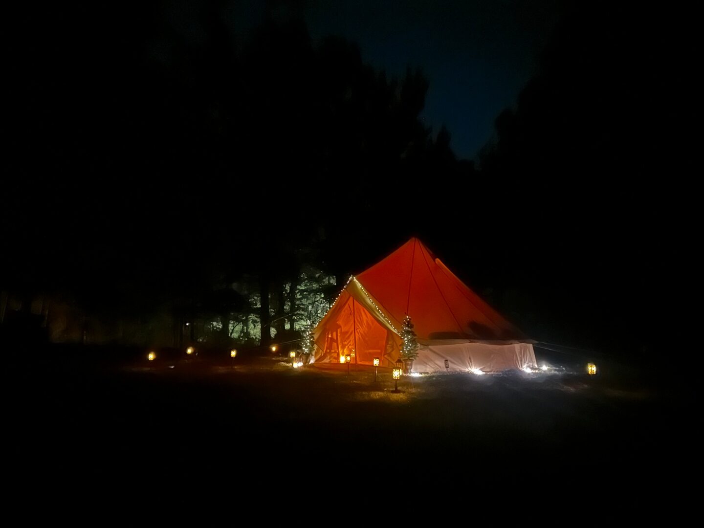 Carpa bell por la noche en el bosque con linternas cálidas