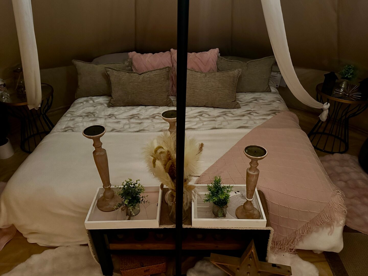 Cama de carpa bell con almohadas rosa y salvia, candelabros de madera y linternas